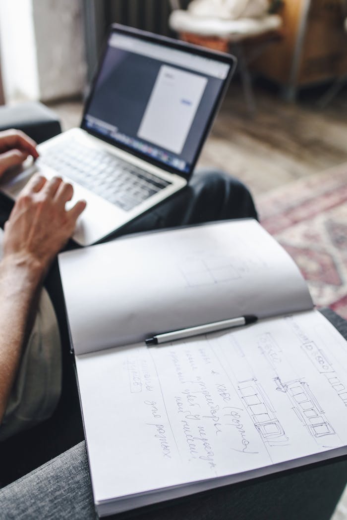 services-01 A person working on a laptop with an open notebook, showcasing a productive work-from-home setup.