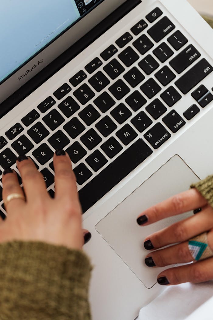 gallery-3 Close-up of hands typing on a MacBook Air keyboard, creating a focused work environment.