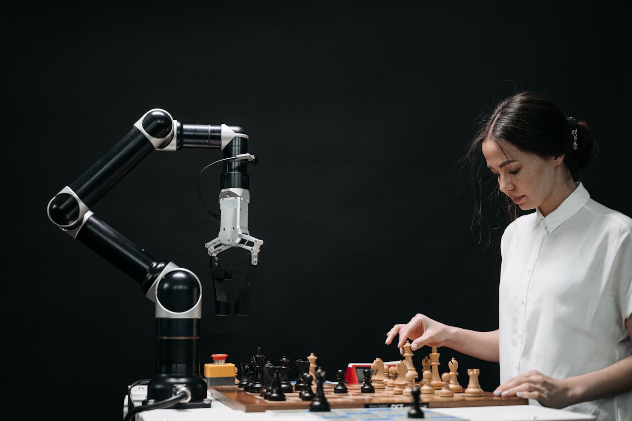contact-img A woman plays chess against a robotic arm, showcasing AI innovation in a modern setting.